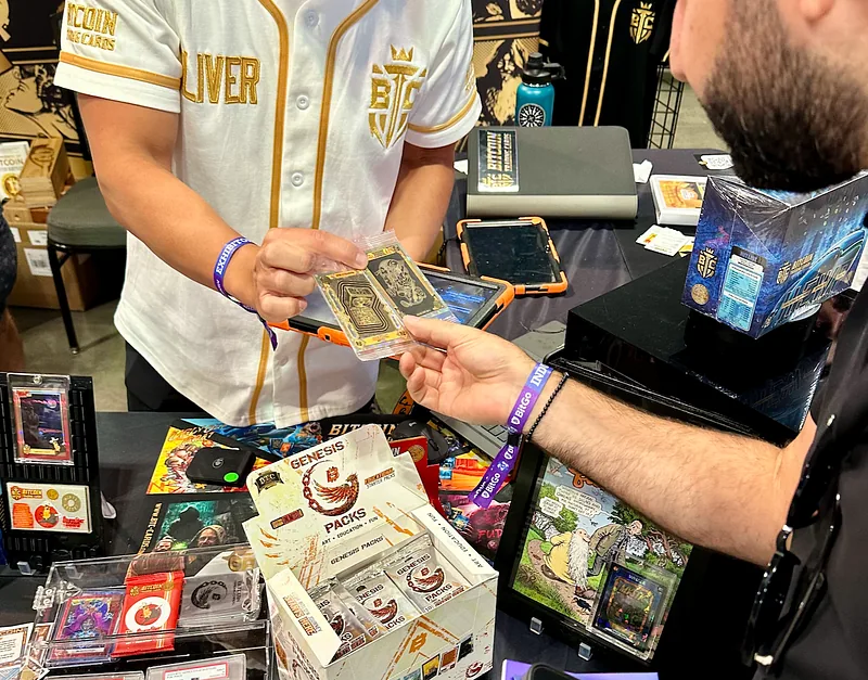 A collector at the booth examining two Bitcoin Trading Cards held in his hands