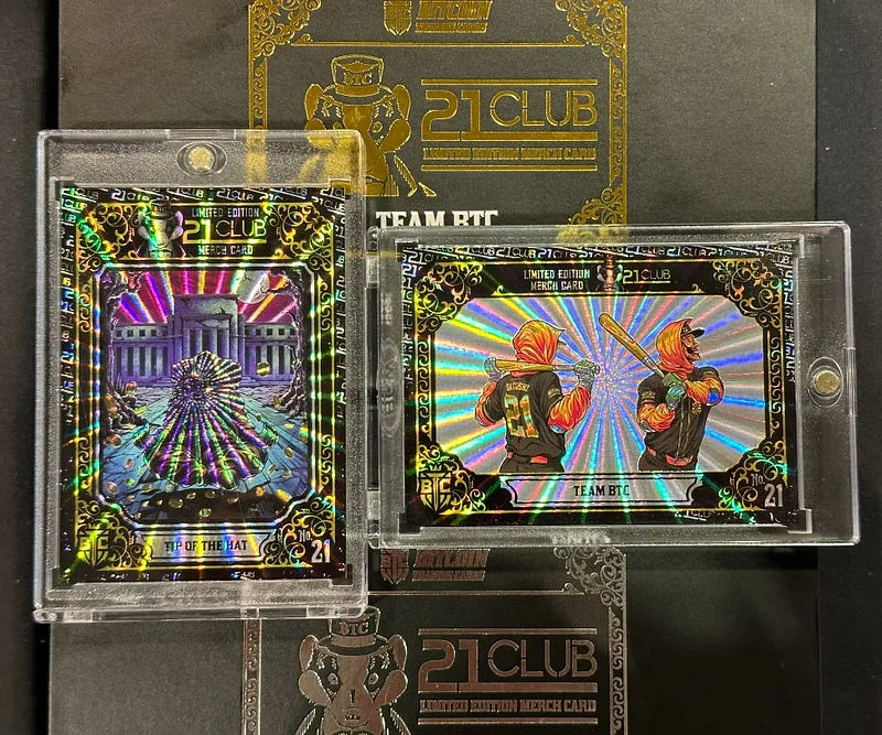 Two holographic 21 Club cards in protective cases on a 21 Club merchandise mat