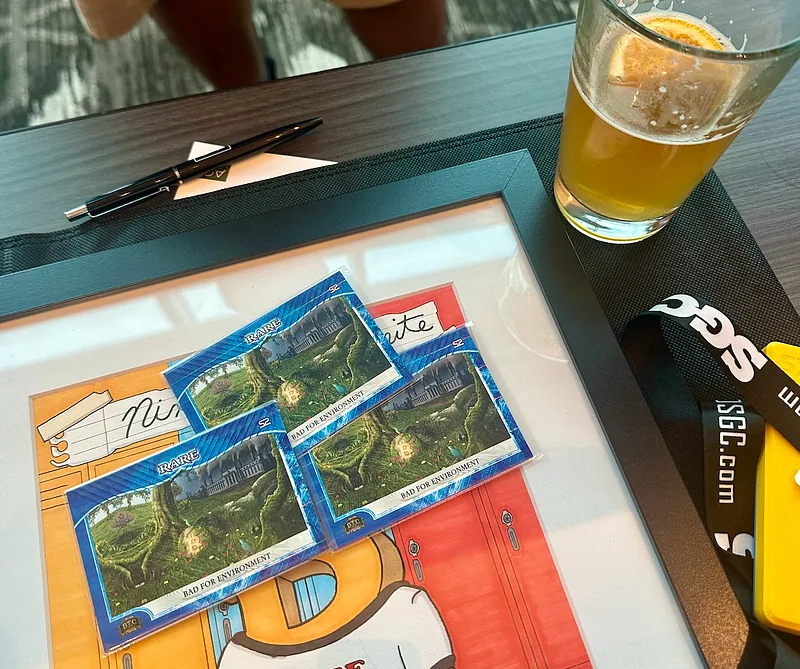 Four Series 2 Orange Pill in a Pack cards laid out on a table beside a glass of beer