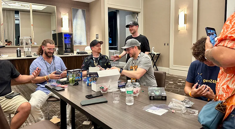 A group of collectors seated around a hotel table, opening Bitcoin Trading Cards packs together